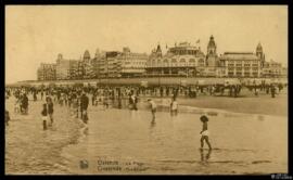 Tarjeta postal circulada de escena costumbrista urbana de baños de ola en la playa de Ostende con...