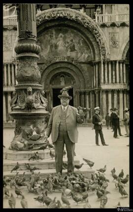 Tarjeta postal de retrato de un hombre sosteniendo palomas a los pies de una farola de la Plaza d...