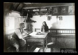 Hombre y mujer sentados en el interior de una casa rural