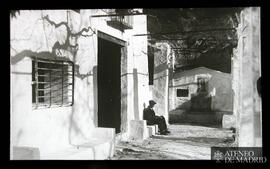 Hombre sentado junto a la entrada de una casa rural