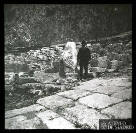 Delfos. Vía sagrada y hombre posando al lado de una escultura